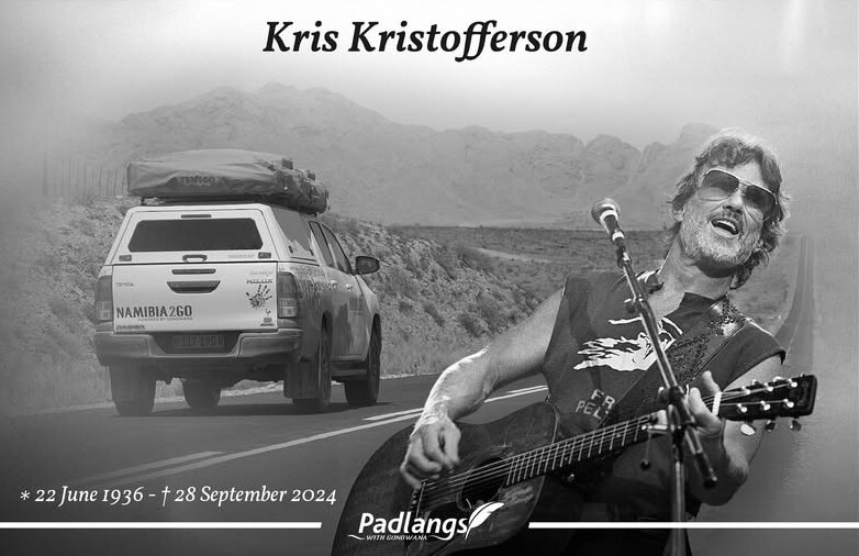 Signboard reading “Wêreldend” on the C27 with the expansive sandy Namib, distant mountains, and big sky in the background.